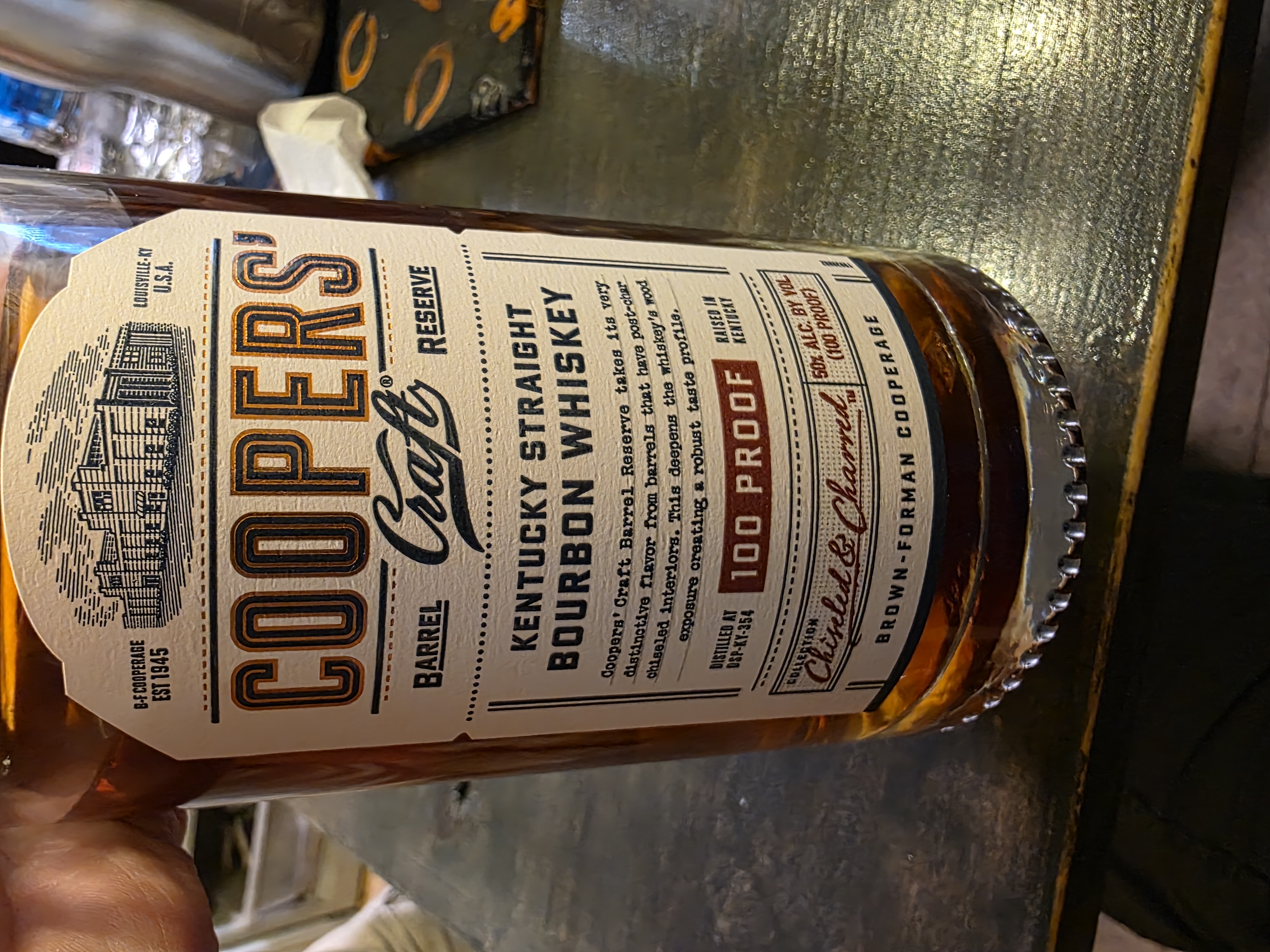 Close-up of the Cooper's Craft Barrel Reserve 100 Proof bottle poured during the night.